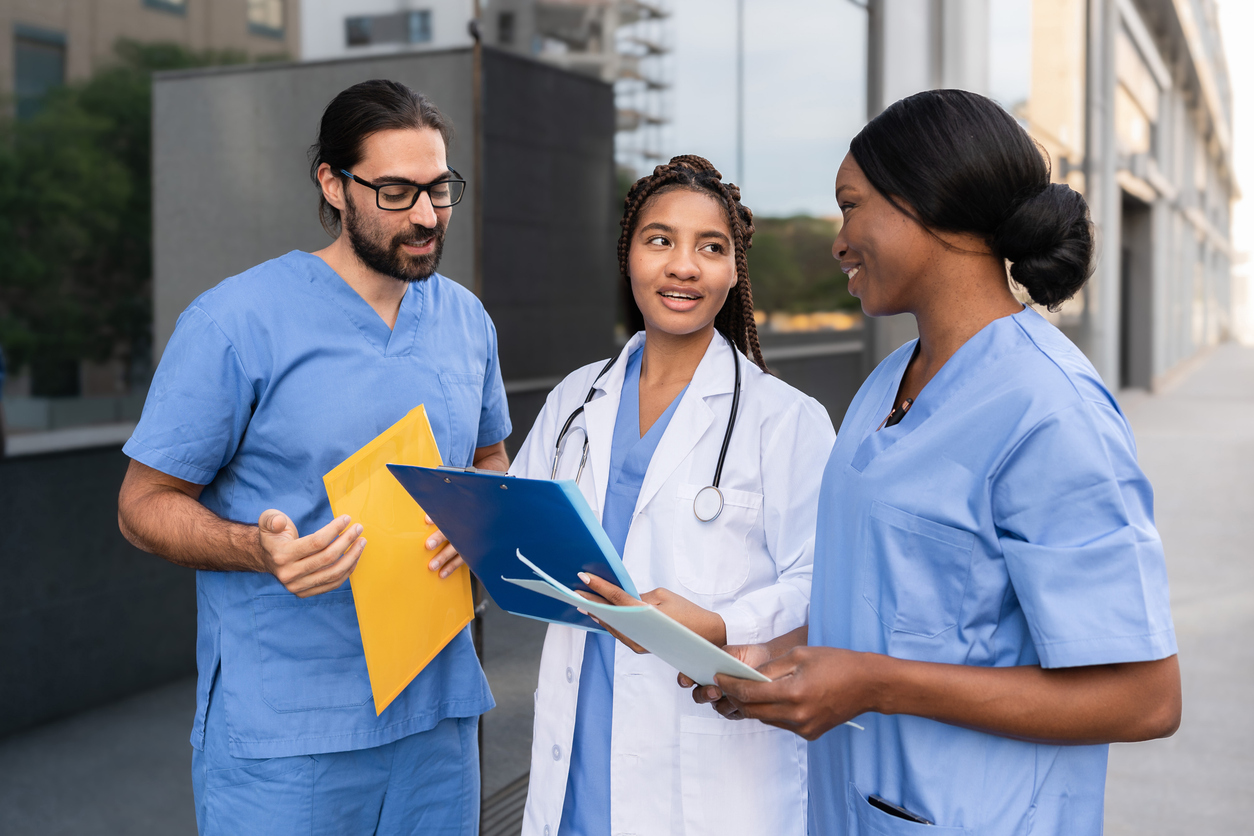 Nurses standing and talking outside of a medical facility.